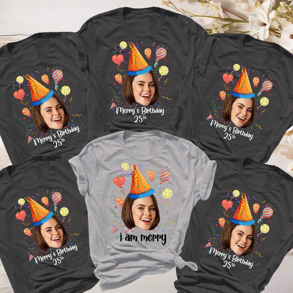 May include: Six gray and light gray t-shirts with a birthday theme. Each shirt features a different person's face with a party hat and confetti. One shirt says "i am merry".