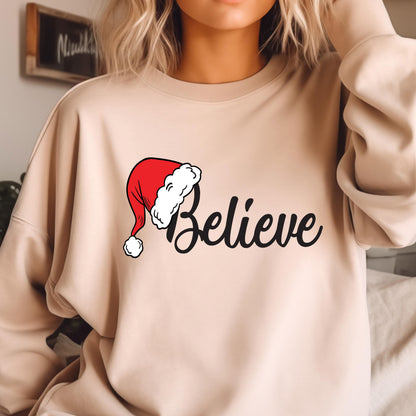 May include: A beige crewneck sweatshirt featuring the word Believe in black cursive script. The letter B is replaced by a red Santa hat with a white fur trim and a white pom-pom at the end. The sweatshirt has long sleeves and a round neckline.