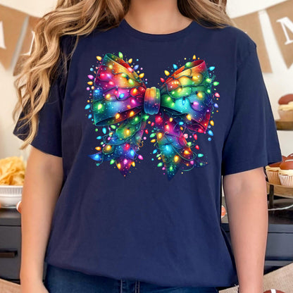 May include: A navy blue t-shirt featuring a large, colorful bow design. The bow is adorned with a string of vibrant, multicolored Christmas lights, creating a festive and eye-catching graphic. The design is centered on the front of the shirt.