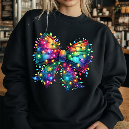 May include: A black long-sleeve sweatshirt featuring a large, central graphic of a decorative bow made entirely of vibrant, multi-colored glowing Christmas string lights in shades of red, blue, green, yellow, and purple against a dark background.