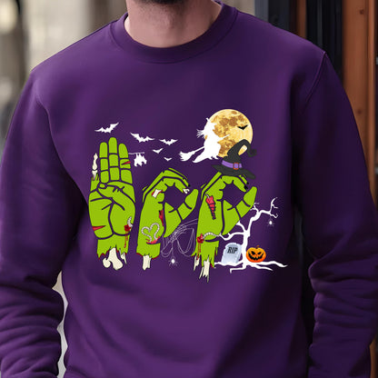 May include: A purple sweatshirt with a Halloween-themed design. The design features green zombie hands spelling out the word "BOO", bats, a full moon, a witch, a tombstone, and a jack-o'-lantern. The sweatshirt is made of a soft material.