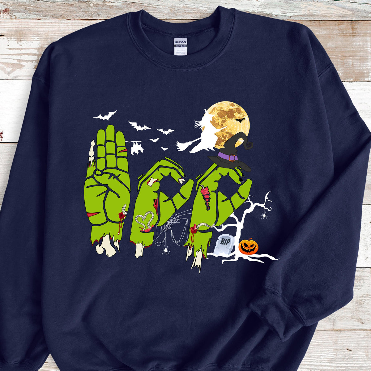 May include: Navy blue sweatshirt with a Halloween-themed graphic. The design features green zombie hands spelling out "BOO" in American Sign Language, with bats, a full moon, a witch's hat, and a jack-o'-lantern.