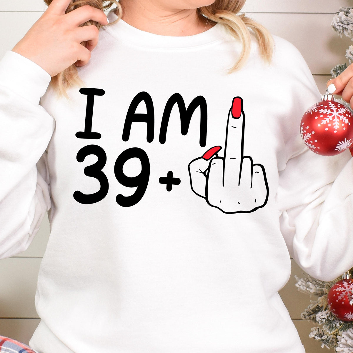 May include: White sweatshirt with black text that reads "I AM 39+" and a black and white illustration of a hand giving the middle finger with red nail polish.