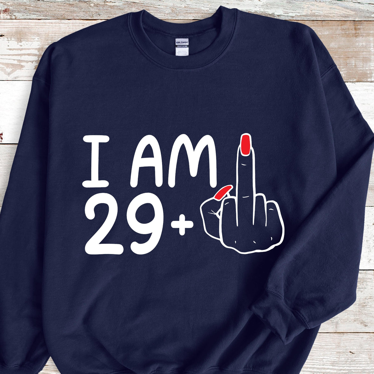 May include: A navy blue sweatshirt with white text that reads "I AM 29+" and a black hand with red fingernails giving the middle finger.