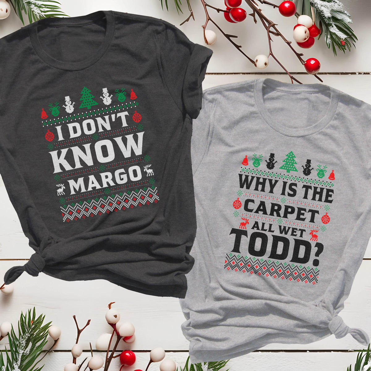 May include: Two Christmas-themed t-shirts. One is dark gray with the text "I DON'T KNOW MARGO" in white, red, and green. The other is light gray with "WHY IS THE CARPET ALL WET TODD?" in similar colors. Both shirts have festive patterns.