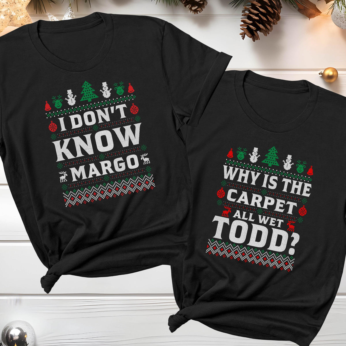 May include: Two black t-shirts with Christmas-themed text. One reads "I DON'T KNOW MARGO" in white, green, and red, with festive graphics. The other says "WHY IS THE CARPET ALL WET TODD?" with similar colors and designs.