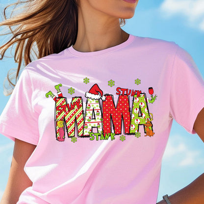 May include: A light pink short-sleeve t-shirt featuring a graphic print of the word MAMA in large, patterned letters. The design includes red and green stripes, polka dots, and small green character illustrations with the text STINK STANK STUNK.
