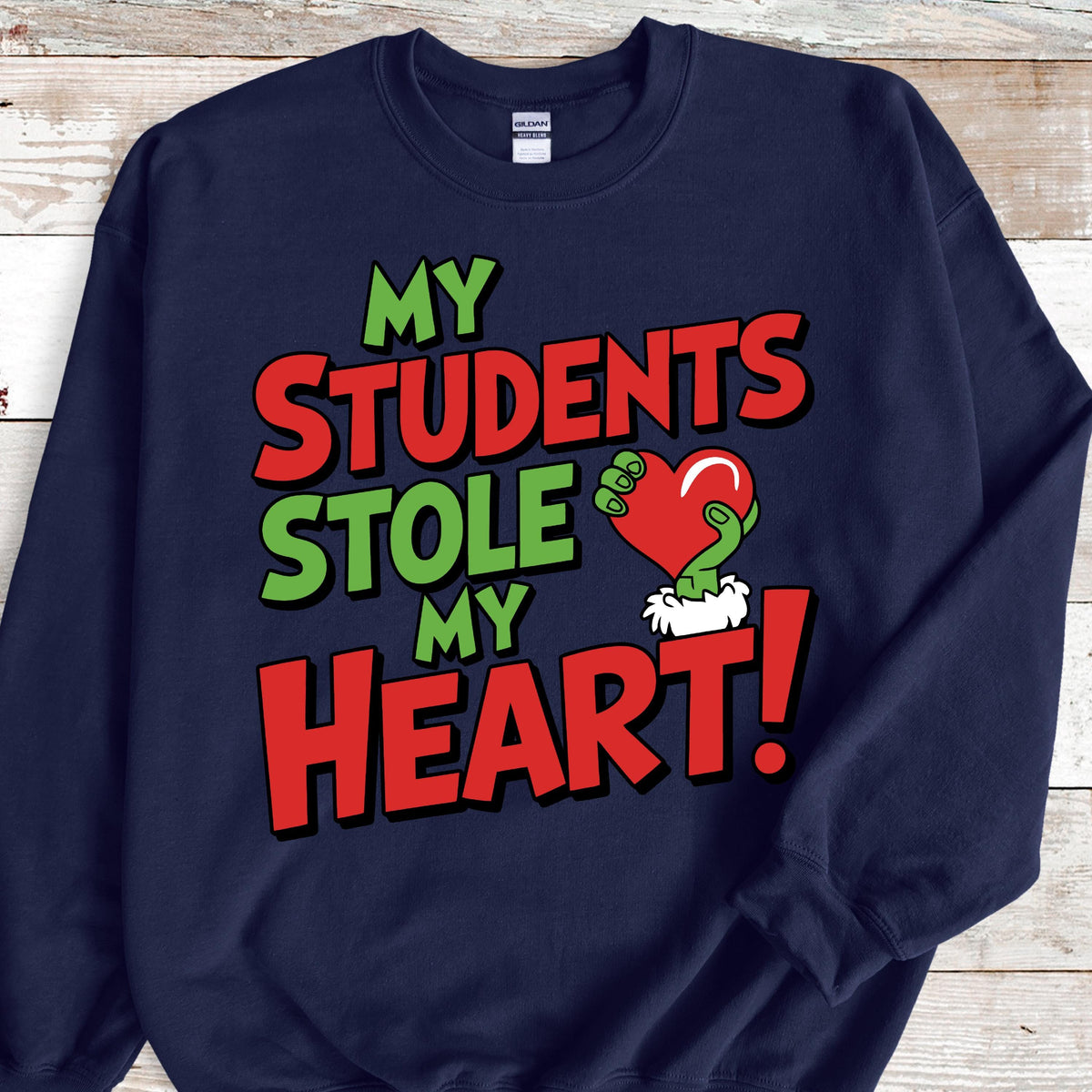 May include: Navy blue sweatshirt with the text "MY STUDENTS STOLE MY HEART!" in red and green. The design includes a green hand holding a red heart. A fun and festive design for teachers.