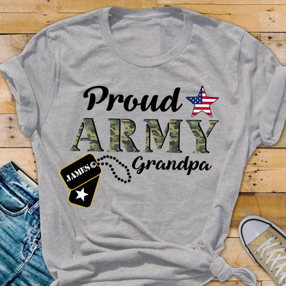 May include: A light gray t-shirt with the words "Proud ARMY Grandpa" in black and camouflage green lettering. An American flag star graphic is above the word "Army". A dog tag with the name "James" is also featured.
