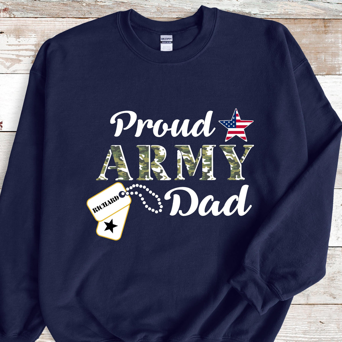 May include: Navy blue sweatshirt with the words "Proud Army Dad" in white script and camouflage print. A star with the American flag design and a dog tag with the name "Richard" are also featured.