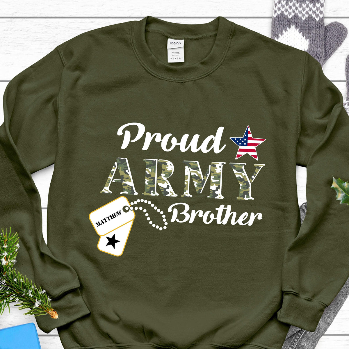 May include: An olive green sweatshirt with the words "Proud ARMY Brother" in white. The word "ARMY" is in a camouflage pattern. An American flag star graphic and a dog tag with the name "Matthew" are also featured.