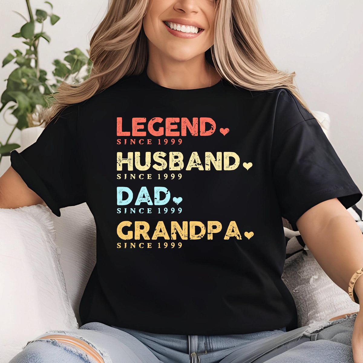 May include: Black t-shirt with the words "LEGEND, HUSBAND, DAD, GRANDPA" in red, yellow, and blue text. Each word is followed by "SINCE 1999" and a heart symbol. A casual tee for a family member.