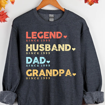 May include: Dark gray sweatshirt with the words "LEGEND, HUSBAND, DAD, GRANDPA" in red, yellow, and blue, with the text "SINCE 1999" below each word. A perfect gift for a loved one.