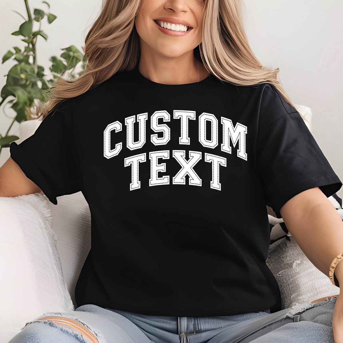 May include: Black t-shirt with the text "CUSTOM TEXT" in a white, collegiate-style font. The shirt has short sleeves and a relaxed fit. The text is outlined with a dotted border.