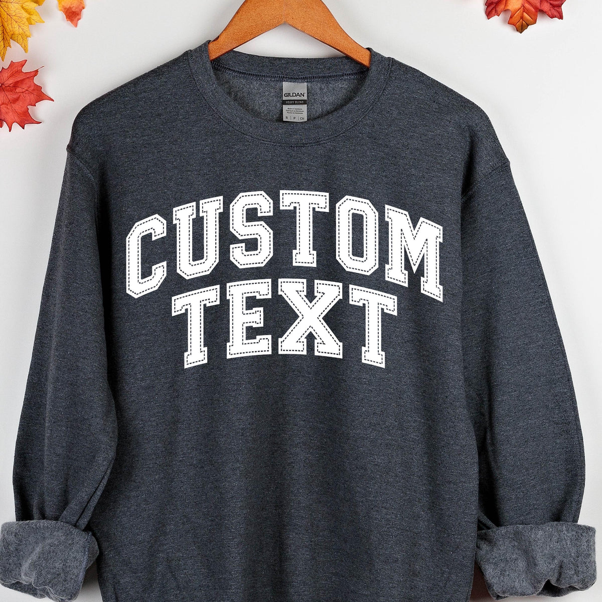 May include: A dark gray sweatshirt with white text that says "CUSTOM TEXT" in a varsity style font.