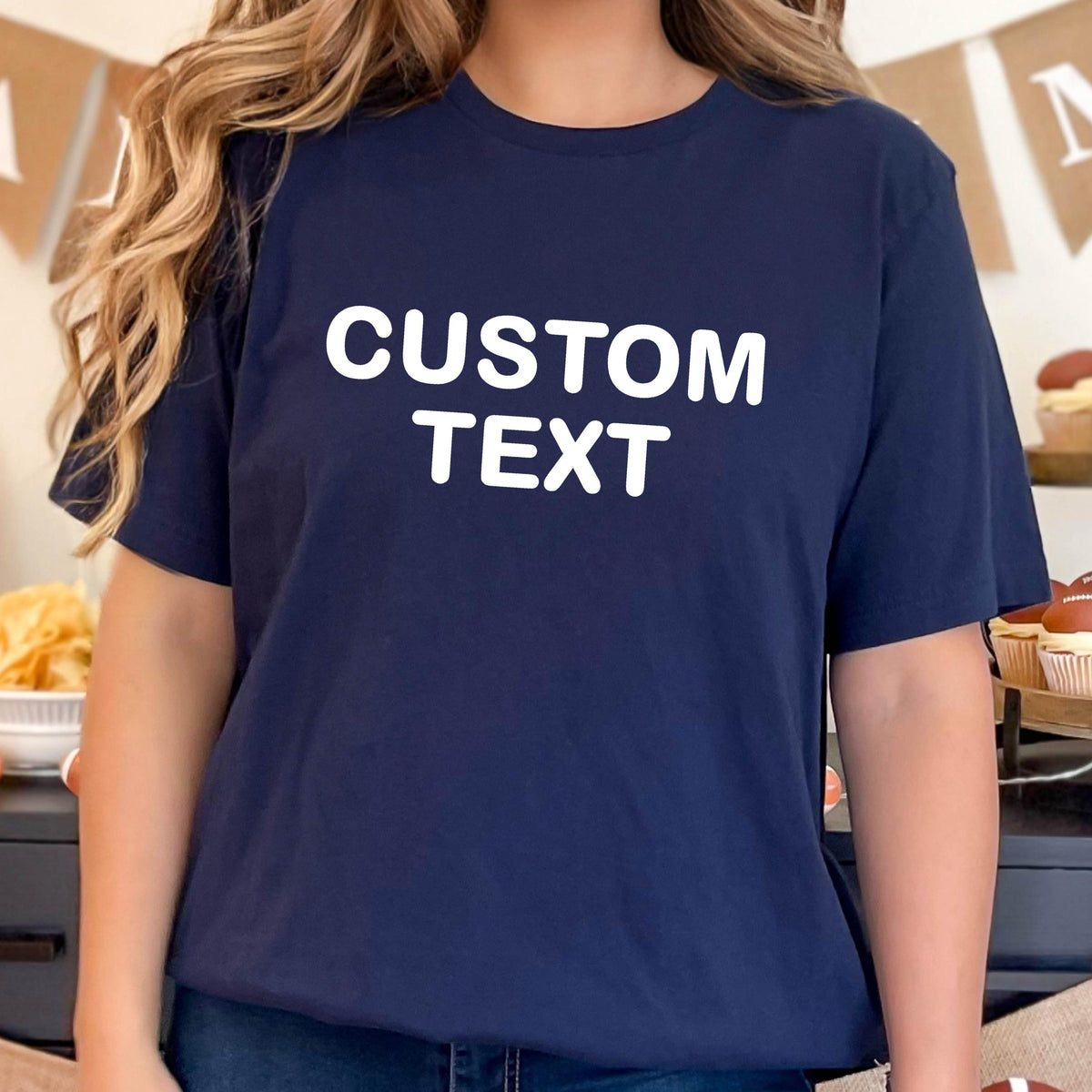 May include: A navy blue short-sleeved t-shirt featuring the words CUSTOM TEXT printed in bold white capital letters across the center of the chest. The garment has a classic crew neckline and a straight hemline, providing a simple and clean look.