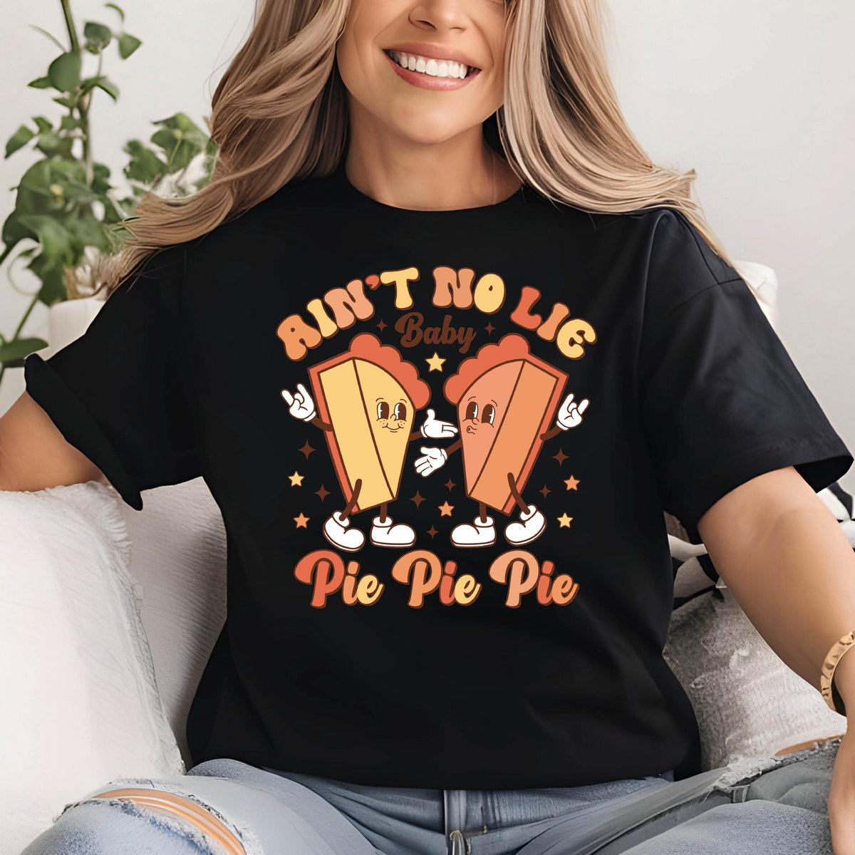 May include: Black t-shirt with a retro graphic featuring two cartoon pie slices with arms and legs. The text reads "Ain't No Lie Baby Pie Pie Pie" in orange and yellow.
