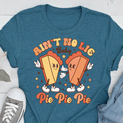 May include: Teal t-shirt featuring a retro graphic with two cartoon pie slices with arms and legs. The text reads "Ain't No Lie Baby" above the pies and "Pie Pie Pie" below. The design has a vintage, groovy aesthetic.