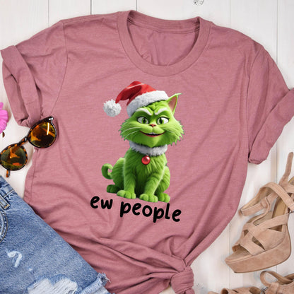 May include: A mauve short-sleeved t-shirt featuring a graphic of a green cat wearing a red and white Santa hat and a red collar bell. Below the cat, the text reads "ew people" in black lowercase letters. The shirt has a crew neckline.