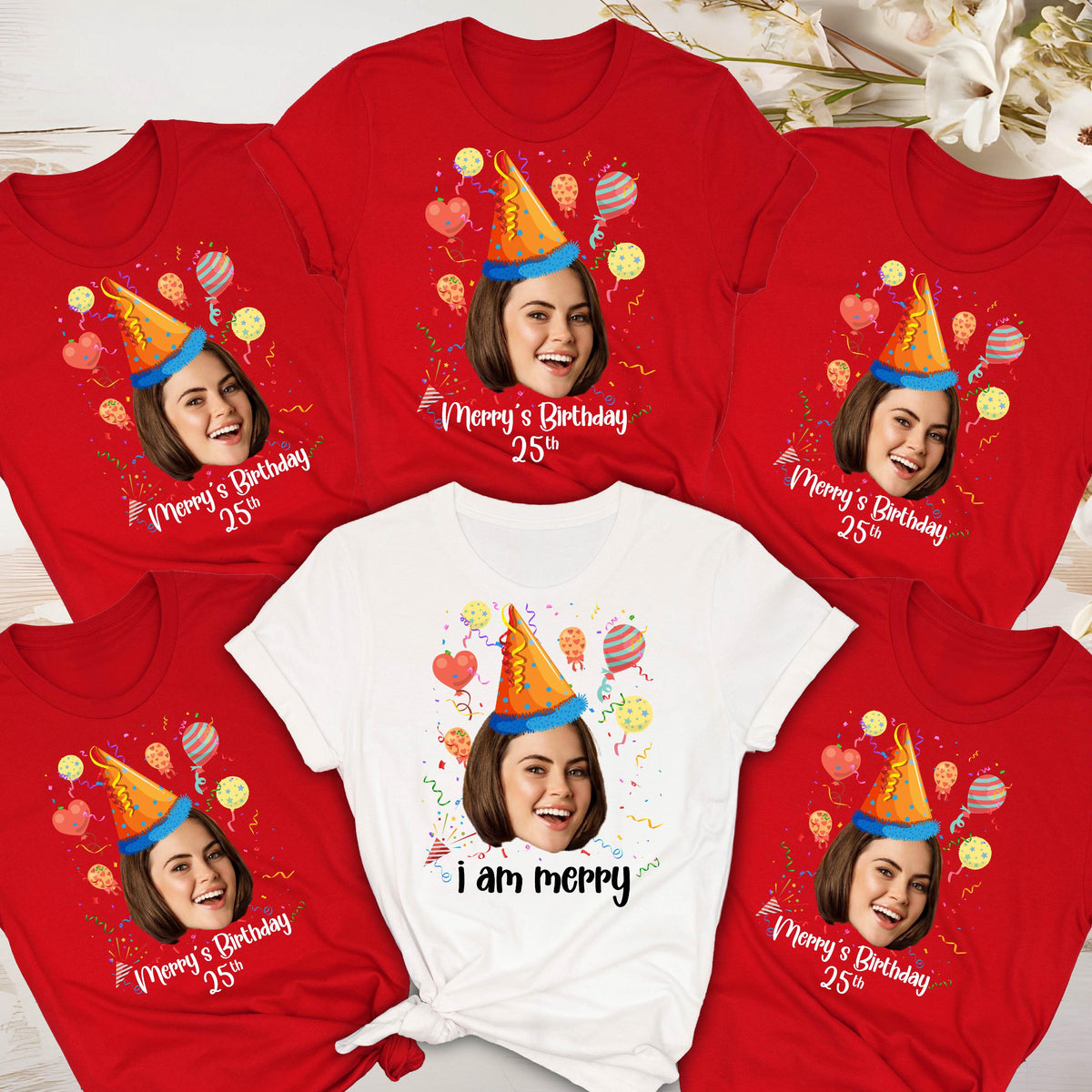 May include: Five red t-shirts with a white t-shirt in the center. Each shirt features a cartoon face with a party hat and balloons. The text on the red shirts reads "Merry's Birthday 25th". The text on the white shirt reads "I am Merry".
