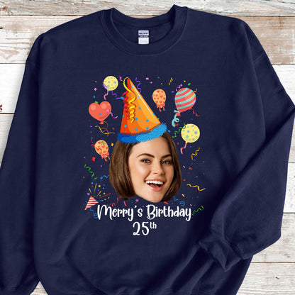 May include: A navy blue sweatshirt with a personalized birthday design. The design features a person's face with a party hat, confetti, and balloons. The text "Merry's Birthday 25th" is printed below the image.