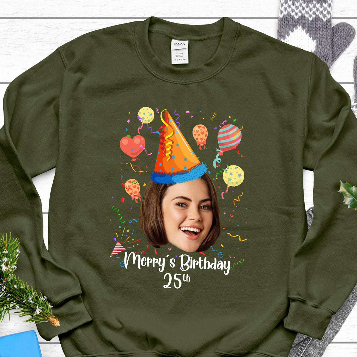 May include: A green sweatshirt with a birthday party design. The design features a person's face in a party hat with confetti and balloons. The text "Merry's Birthday 25th" is printed on the sweatshirt.