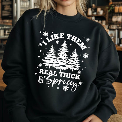 May include: A black crewneck sweatshirt featuring a white graphic print of three pine trees surrounded by snowflakes. The text reads I LIKE THEM REAL THICK & SPRUCEY in a combination of bold block lettering and a decorative script font style.