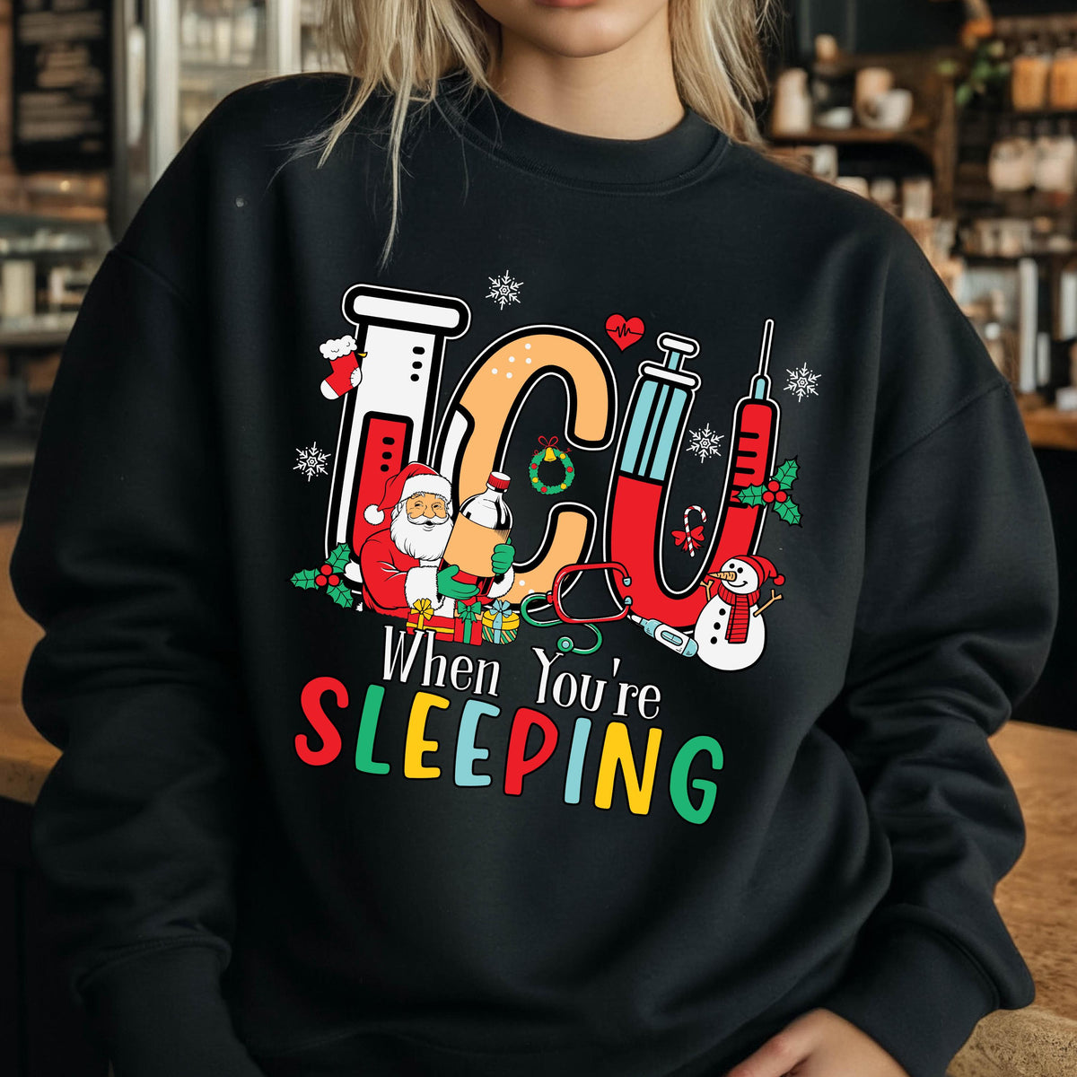 May include: Black sweatshirt with a colorful graphic design featuring the letters "ICU" with medical and Christmas-themed elements. The text "When You're SLEEPING" is below the graphic.
