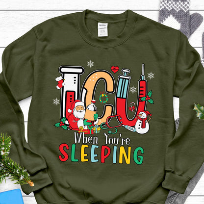 May include: Green sweatshirt with a festive ICU design. The design includes the letters "ICU" in a medical theme with a Santa Claus, snowman, and the text "When You're Sleeping" in colorful letters. A Christmas-themed gift.