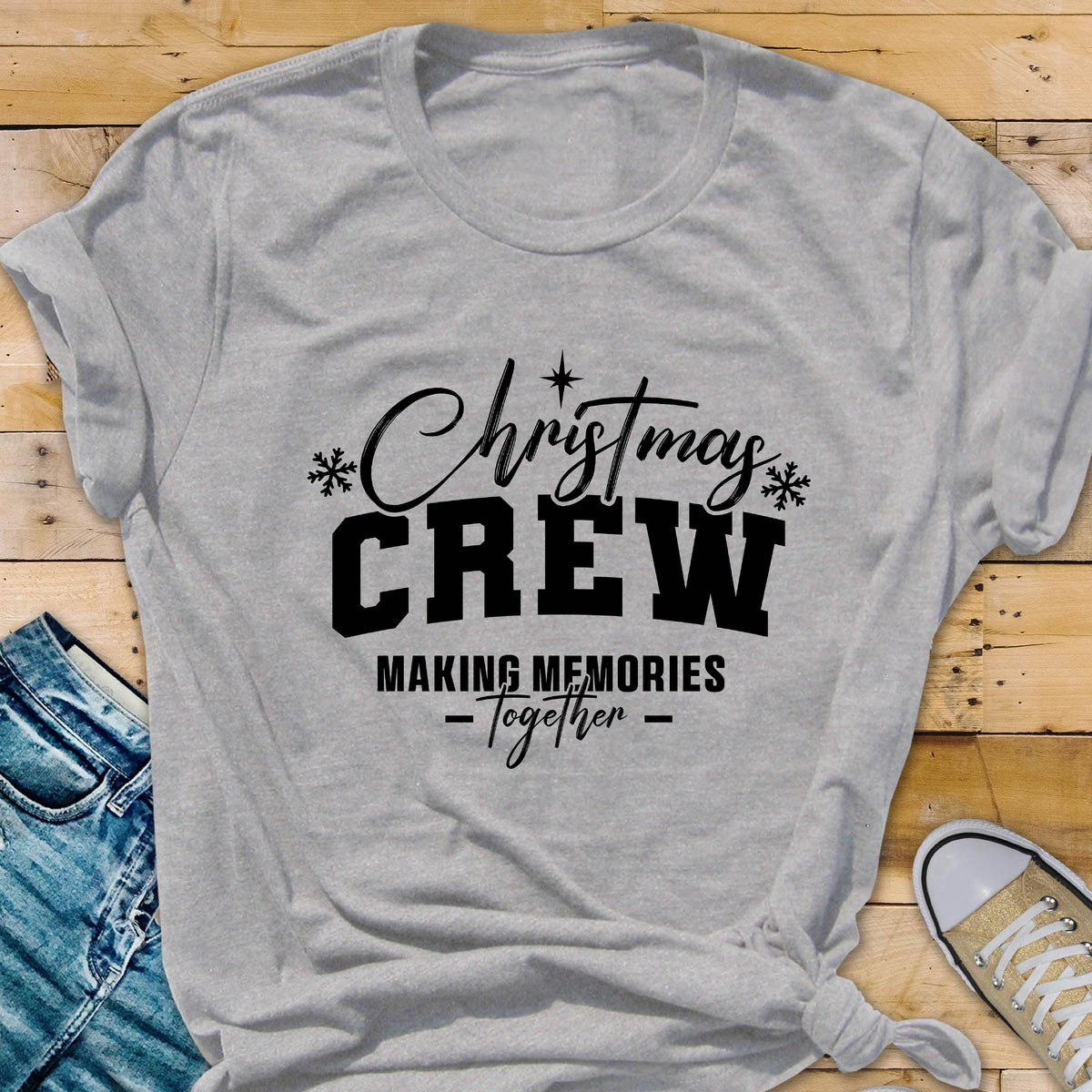 May include: A light gray short-sleeved t-shirt featuring black text that reads Christmas CREW MAKING MEMORIES Together, accented with small black snowflake icons and a star symbol centered above the word Christmas.