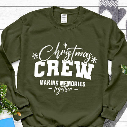 May include: An olive green crewneck sweatshirt featuring white screen-printed text that reads Christmas CREW MAKING MEMORIES Together, accented with two small snowflake icons and a star symbol centered above the word Christmas.