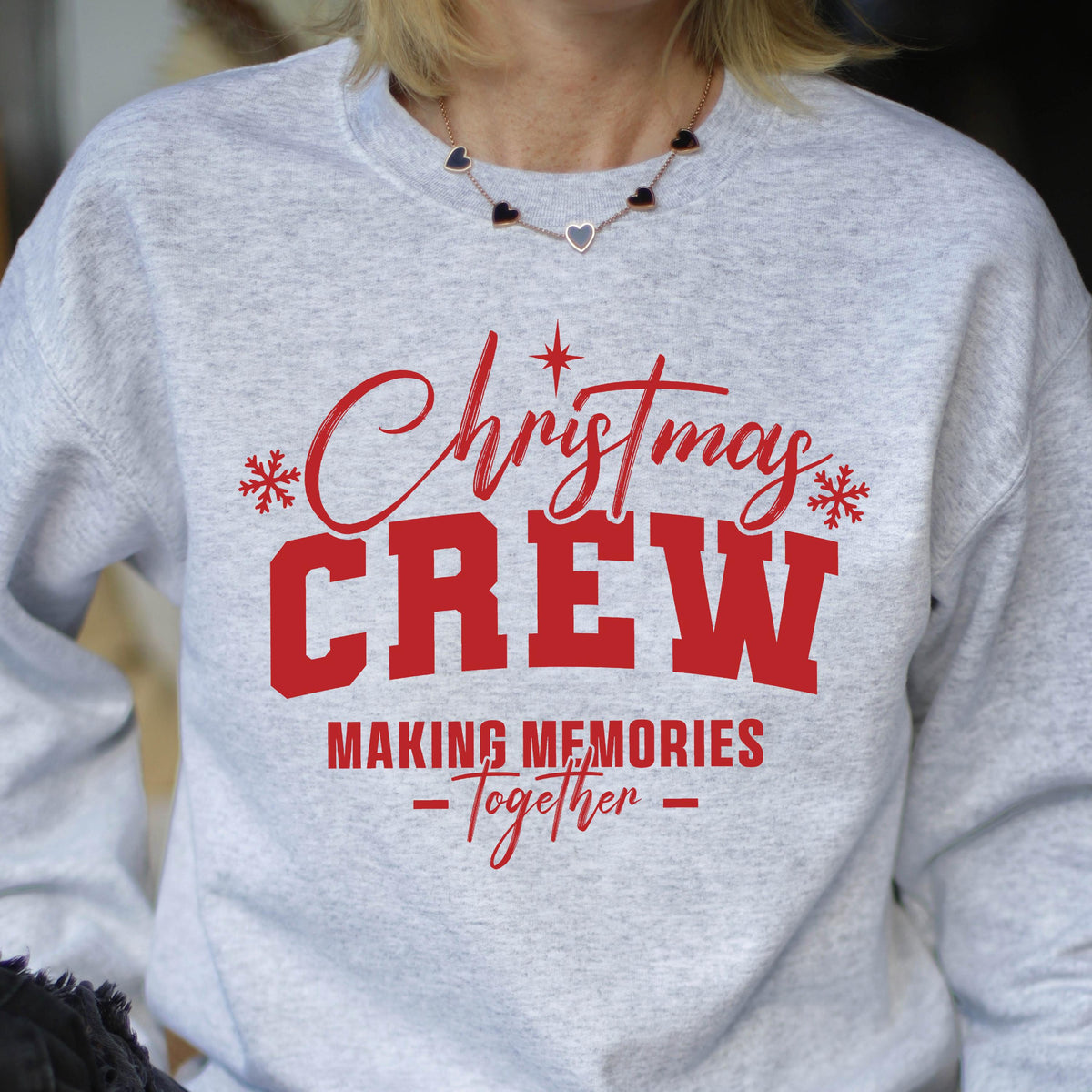 May include: A light gray crewneck sweatshirt featuring red text that reads Christmas CREW MAKING MEMORIES Together, accented with red snowflake and star graphics. The design is centered on the chest of the long-sleeved pullover garment.