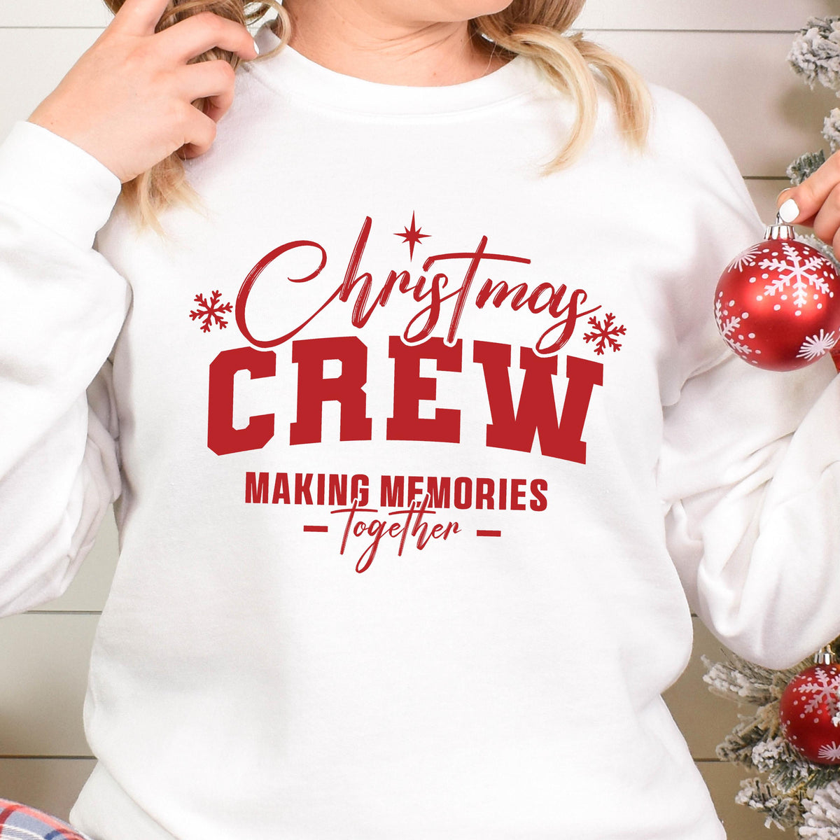 May include: A white long-sleeve sweatshirt featuring red text that reads Christmas CREW MAKING MEMORIES -Together- with small red snowflake and star accents. The design is centered on the chest of the garment, which has a crew neckline.