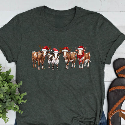 May include: Dark gray t-shirt featuring a festive design of five cows. Each cow is adorned with a Santa hat and some have reindeer antlers and scarves. The cows are brown and white, creating a holiday-themed graphic.