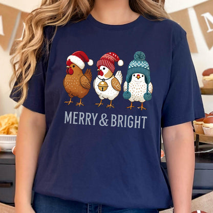 May include: Navy blue t-shirt featuring three cartoon chickens wearing winter hats. The chickens are brown, white, and blue, and the text "MERRY & BRIGHT" is printed below them in white.