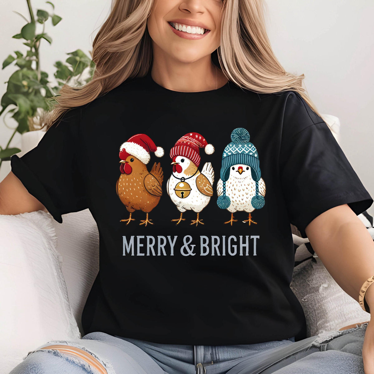 May include: Black t-shirt featuring three cartoon chickens wearing winter hats. The chickens are brown, white, and white with blue accents. The text "MERRY & BRIGHT" is printed below the chickens in white.