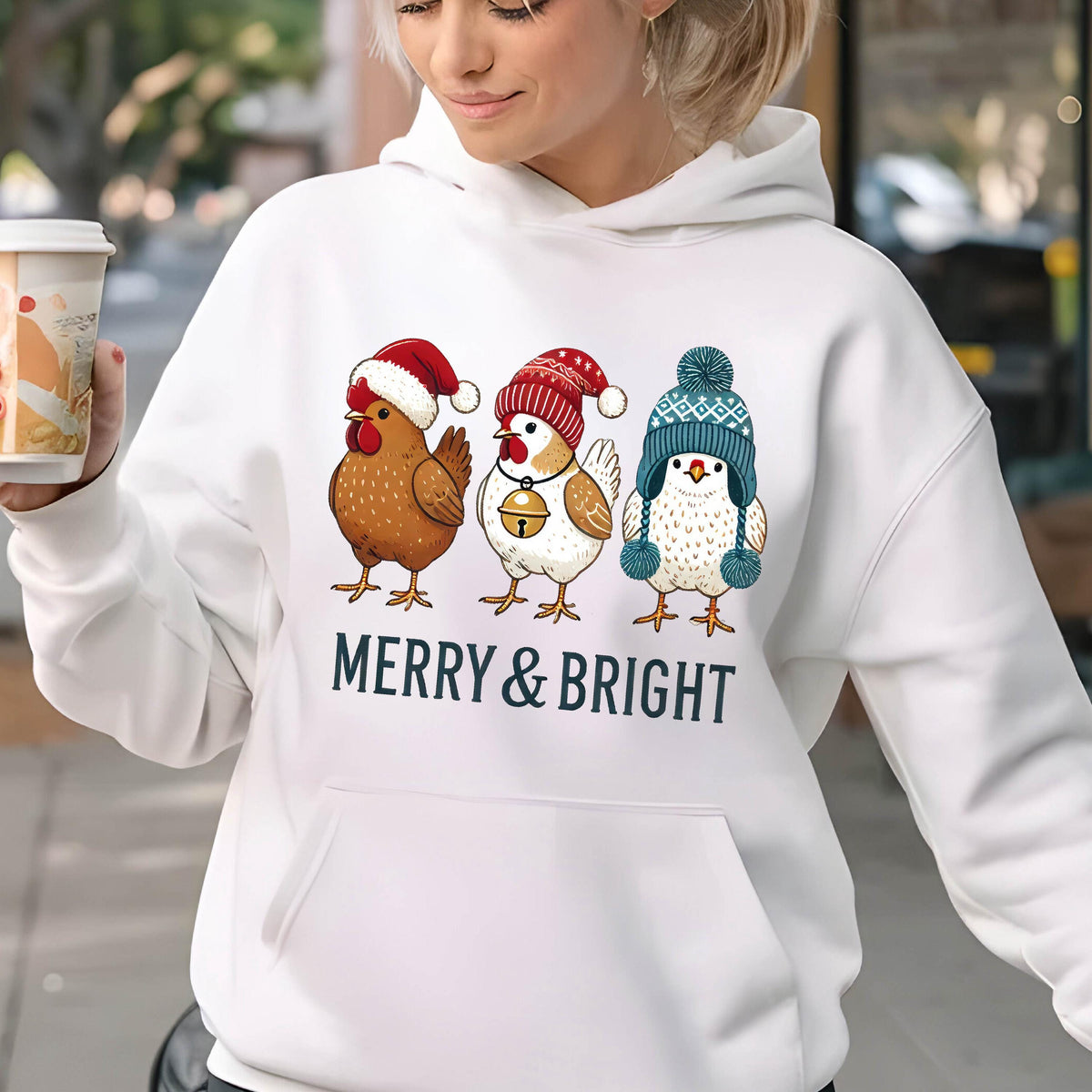 May include: White hooded sweatshirt with a graphic of three chickens wearing Christmas hats and the text "Merry & Bright".