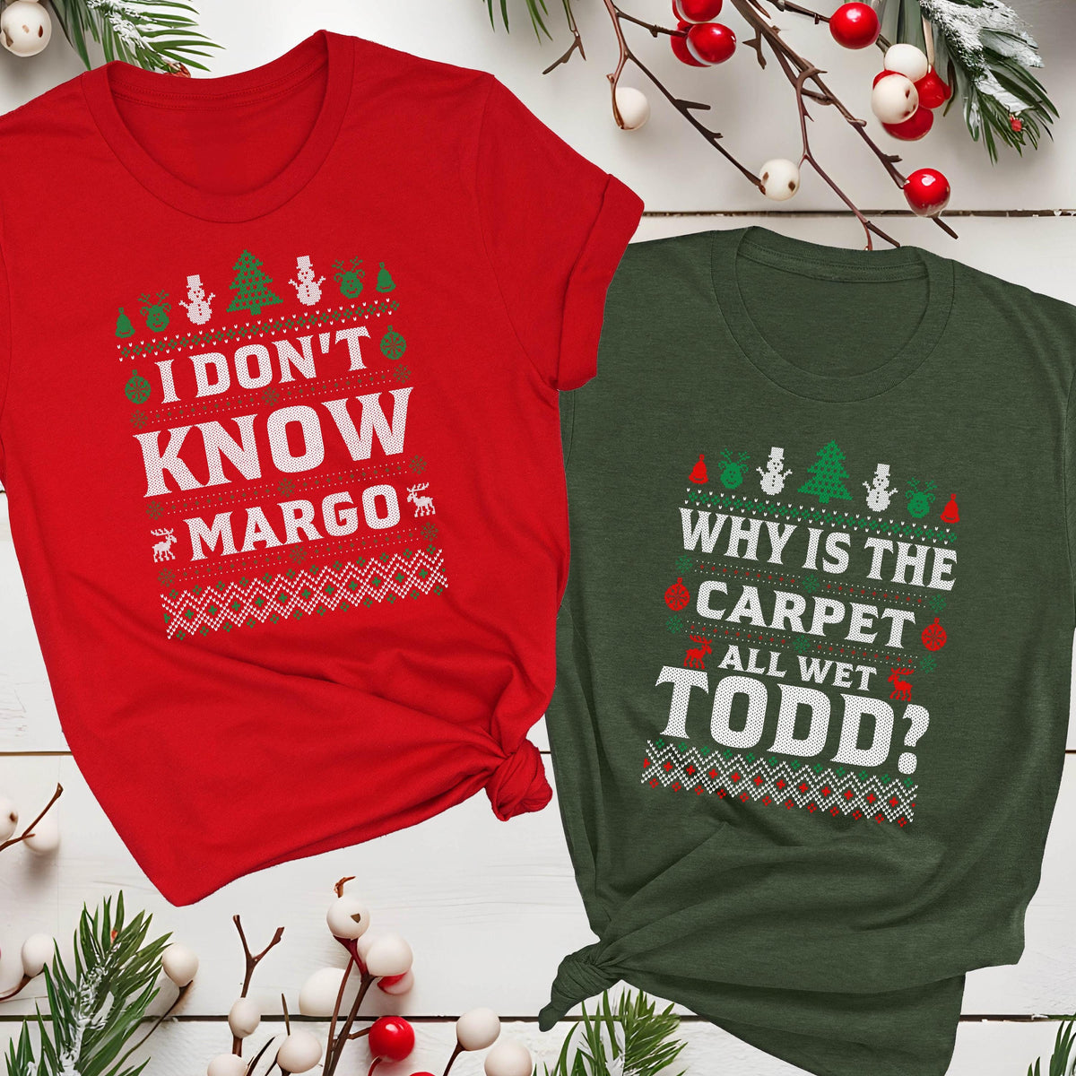 May include: Two Christmas-themed t-shirts. One is red with the text "I DON'T KNOW MARGO" and the other is green with the text "WHY IS THE CARPET ALL WET TODD?". Both shirts have a festive design with trees and snowmen.