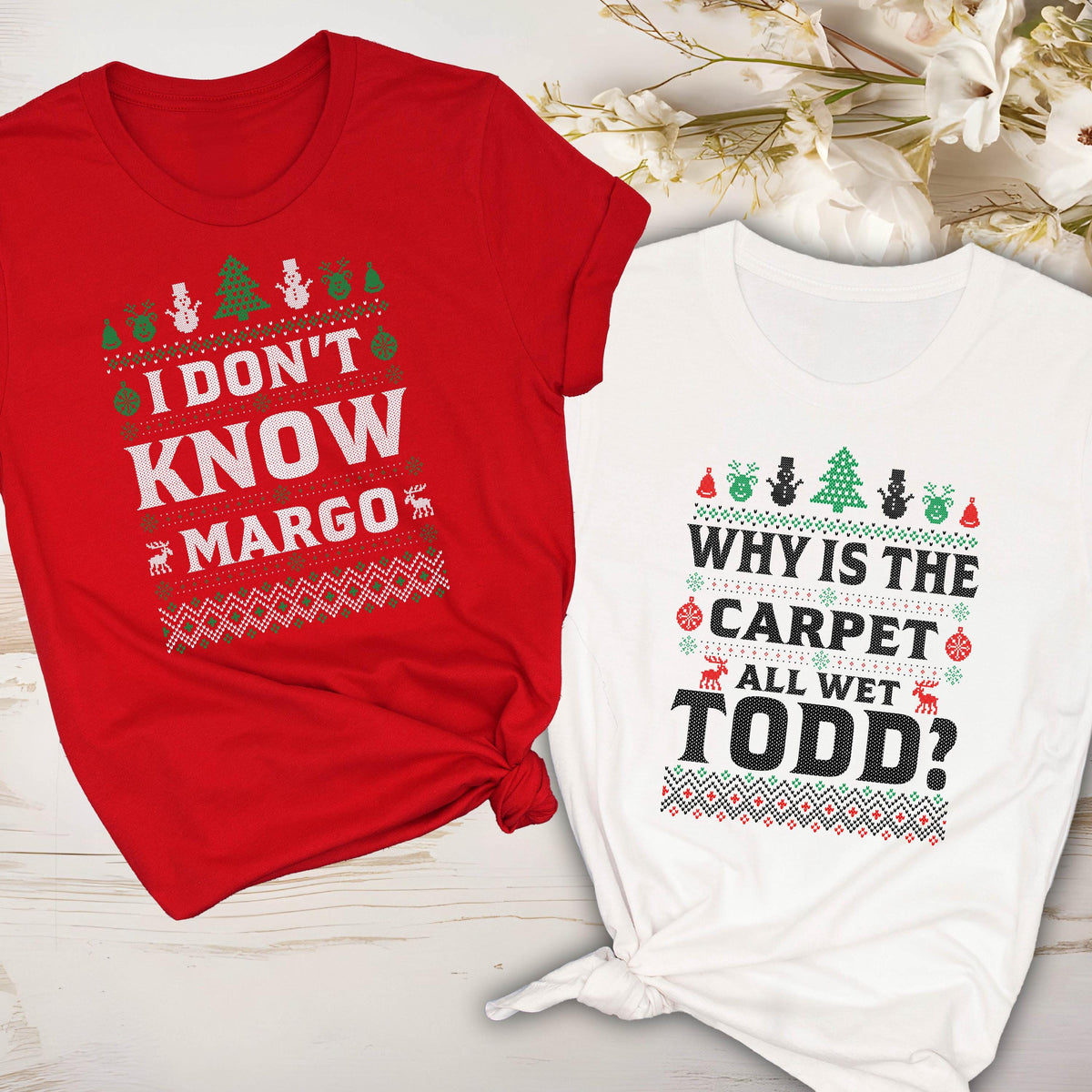 May include: Two Christmas-themed t-shirts. One is red with the text "I DON'T KNOW MARGO" and the other is white with "WHY IS THE CARPET ALL WET TODD?" Both shirts have festive patterns with trees, snowmen, and reindeer.