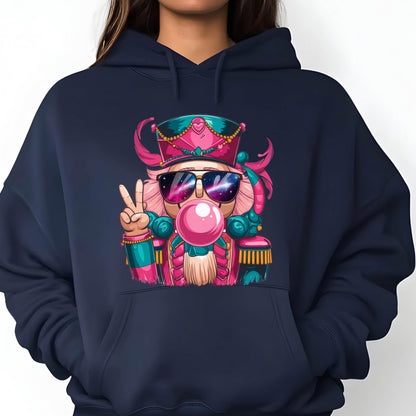 May include: Navy blue hoodie featuring a colorful illustration of a nutcracker wearing sunglasses and blowing a bubblegum bubble. The nutcracker is depicted with pink, teal, and gold accents, giving a playful and festive vibe. The design includes a peace sign.