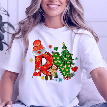 May include: White t-shirt with a colorful graphic design featuring the letters "RN" in red and green, decorated with Christmas-themed elements like a Santa hat, gingerbread man, and Christmas tree.