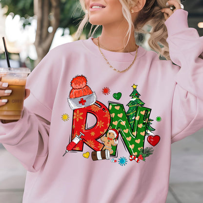 May include: A light pink crewneck sweatshirt featuring a graphic print of the letters RN. The R is red with snowflake patterns and a syringe, while the N is green with heart patterns and a Christmas tree. Includes a nurse hat and gingerbread man.