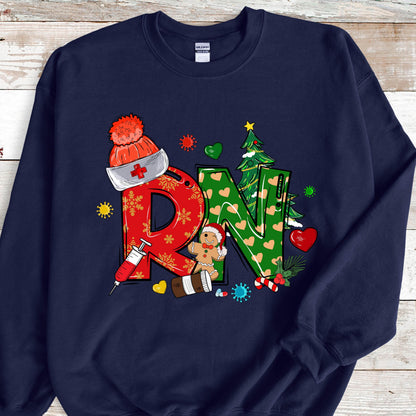 May include: A navy blue crewneck sweatshirt featuring a graphic print of the letters RN. The R is red with snowflakes, and the N is green with hearts. The design includes a nurse hat, a syringe, a gingerbread person, and a Christmas tree.