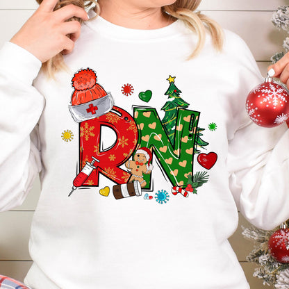 May include: A white long-sleeve sweatshirt featuring a graphic print of the letters RN in red and green with snowflake and heart patterns. The design includes a nurse cap, a syringe, a gingerbread person, a Christmas tree, and virus icons.