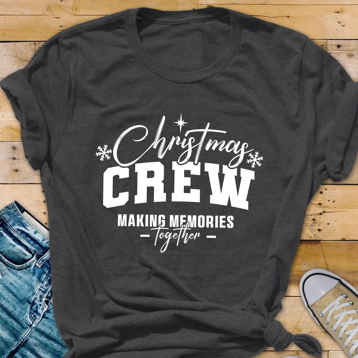 May include: A dark charcoal gray short-sleeve t-shirt featuring white screen-printed text that reads Christmas CREW MAKING MEMORIES Together, accented with small white snowflake icons and a star symbol above the word Christmas.