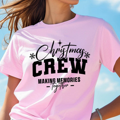 May include: A light pink short-sleeved t-shirt featuring black text that reads Christmas CREW MAKING MEMORIES Together, accented with small black snowflake icons and a star symbol above the word Christmas, centered on the chest.