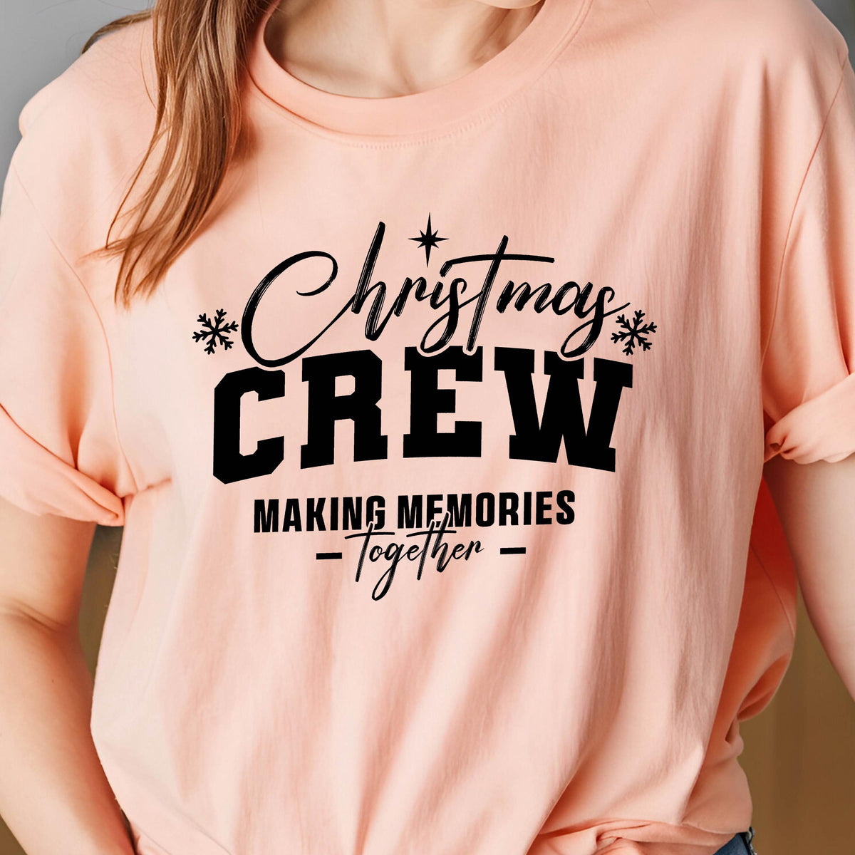 May include: A peach-colored t-shirt featuring black text that reads Christmas CREW MAKING MEMORIES -Together- with small snowflake icons and a star accent above the word Christmas, printed in a mix of script and bold block lettering.