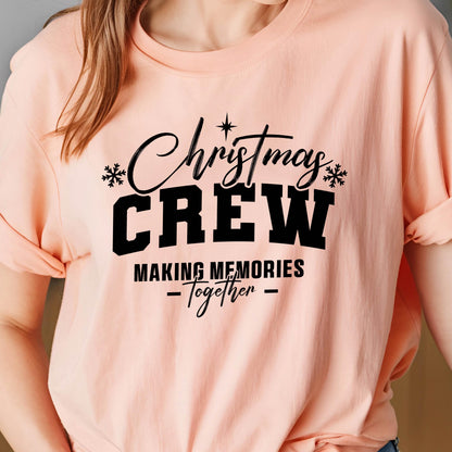 May include: A peach-colored t-shirt featuring black text that reads Christmas CREW MAKING MEMORIES -Together- with small snowflake icons and a star accent above the word Christmas, printed in a mix of script and bold block lettering.