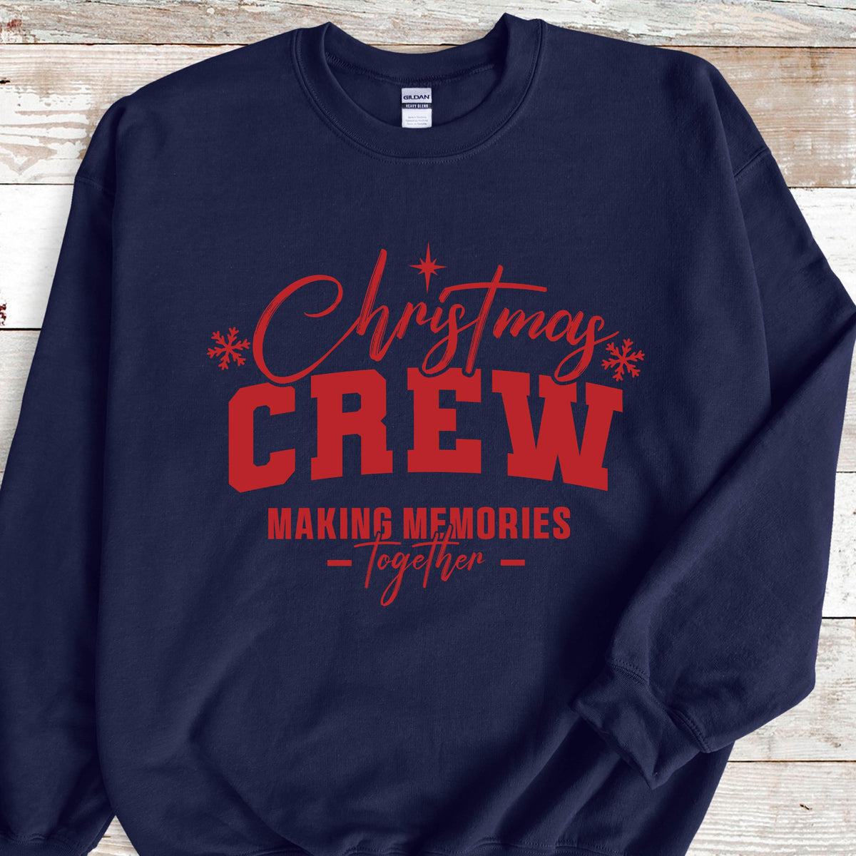 May include: A navy blue crewneck sweatshirt featuring red text that reads Christmas CREW MAKING MEMORIES Together, accented with red snowflake icons and a small star symbol centered above the word Christmas, printed on the front chest.