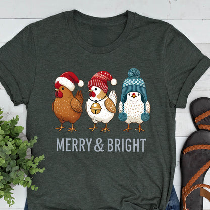 May include: Dark gray t-shirt featuring three cartoon chickens wearing winter hats. The chickens are brown, white, and blue, with red and blue hats. The text "MERRY & BRIGHT" is printed in white below the chickens.